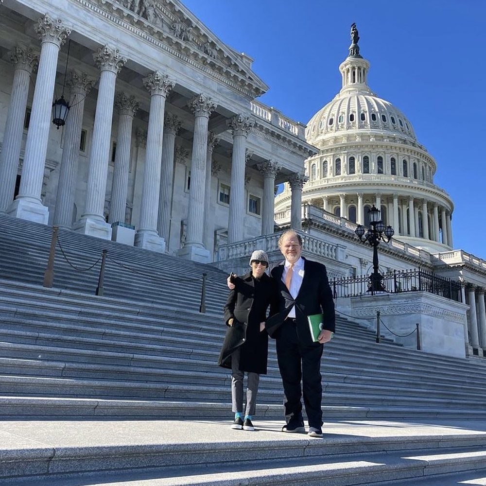 A woman and a man stand in front of the U.S. Capitol