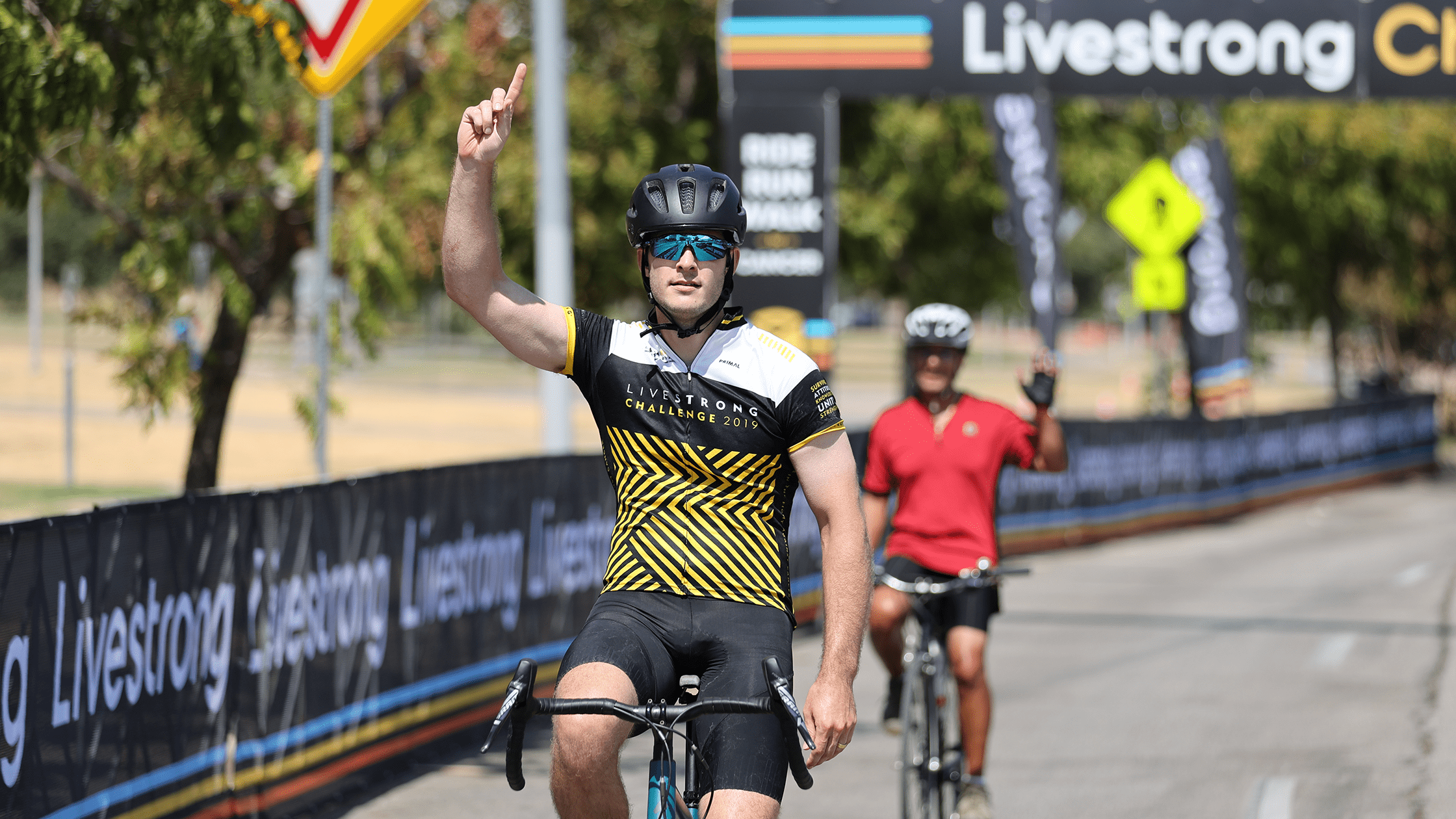 Cyclist points to the sky after crossing finish line