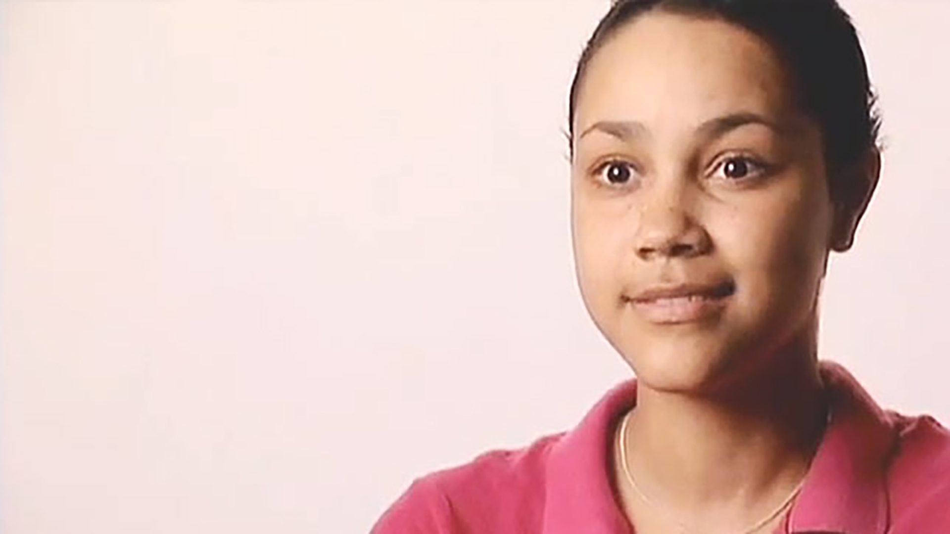 A young woman wearing a pink polo shirt being interviewed