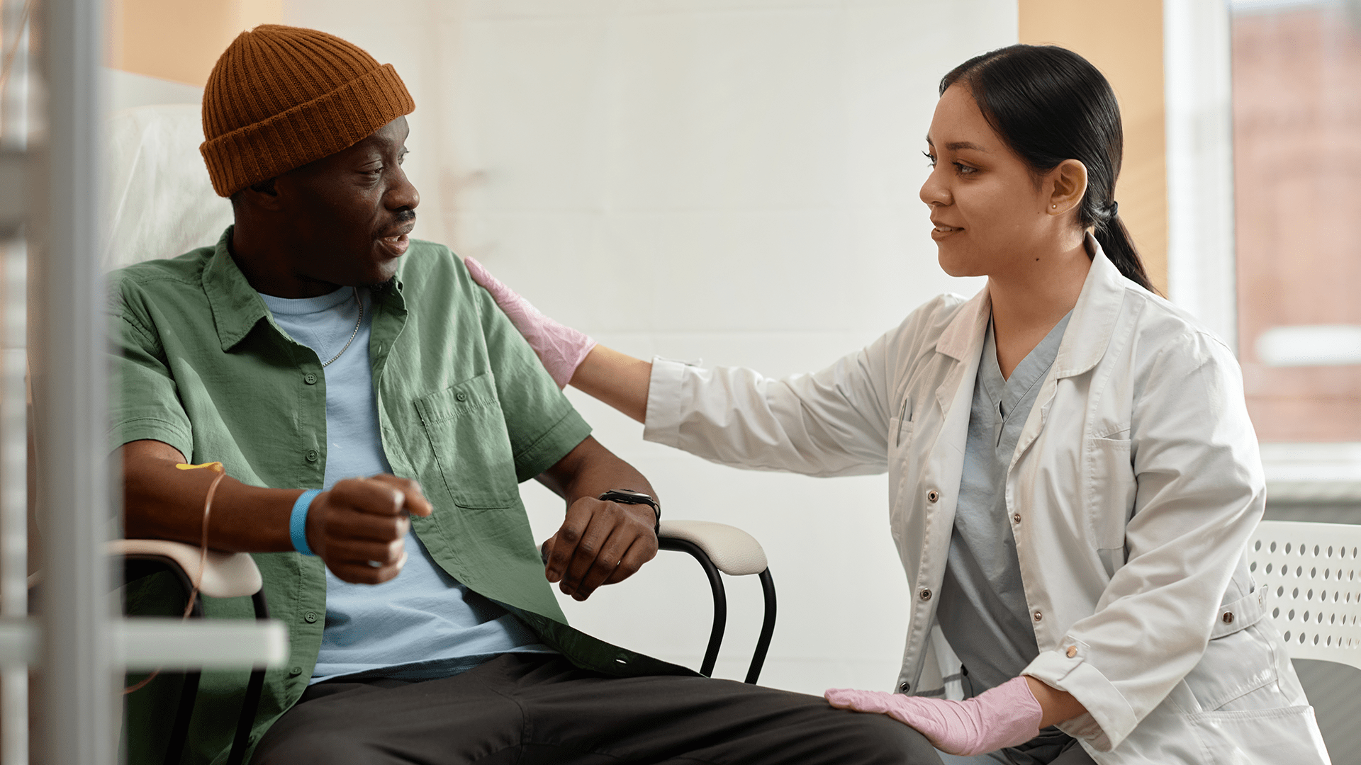 A doctor comforts her male patient who is sitting in a chair receiving a treatment.