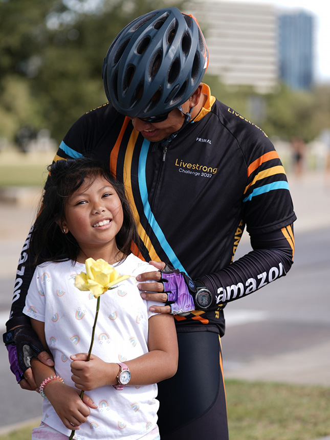 Father in cyclist gear embracing daughter with rose