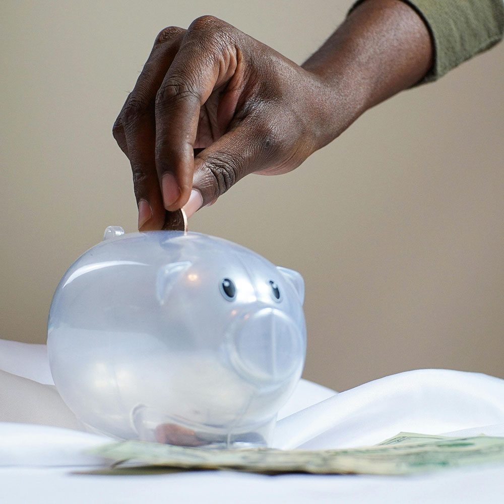 Hand placing coin in a piggy bank