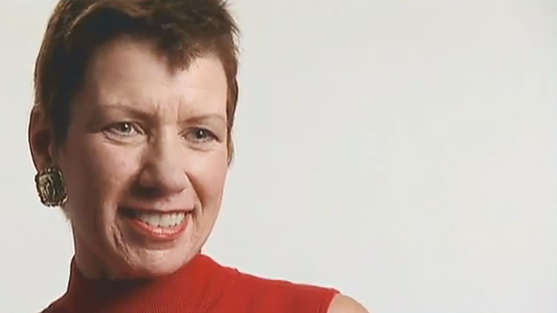 A portrait of an adult woman with short hair and a red sleeveless shirt