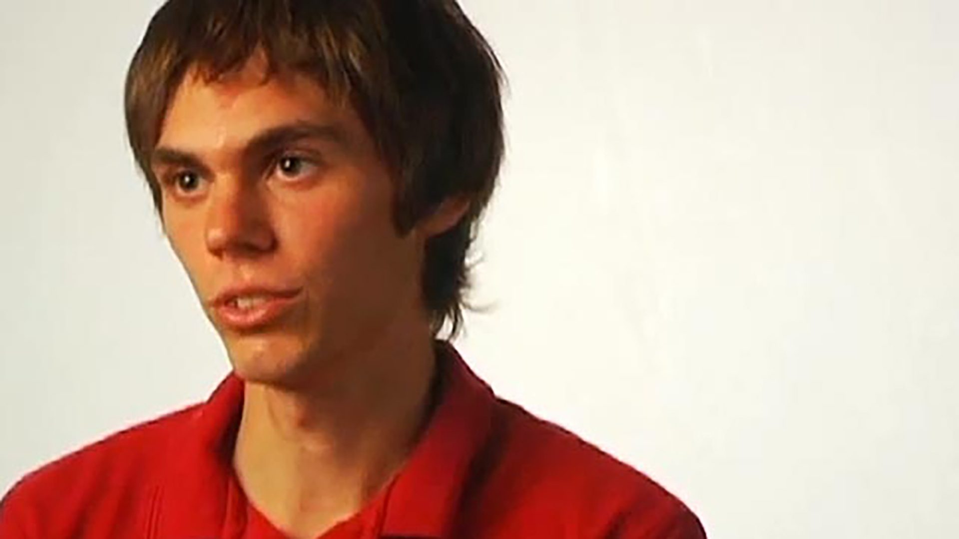 A young man wearing a red shirt against a white background