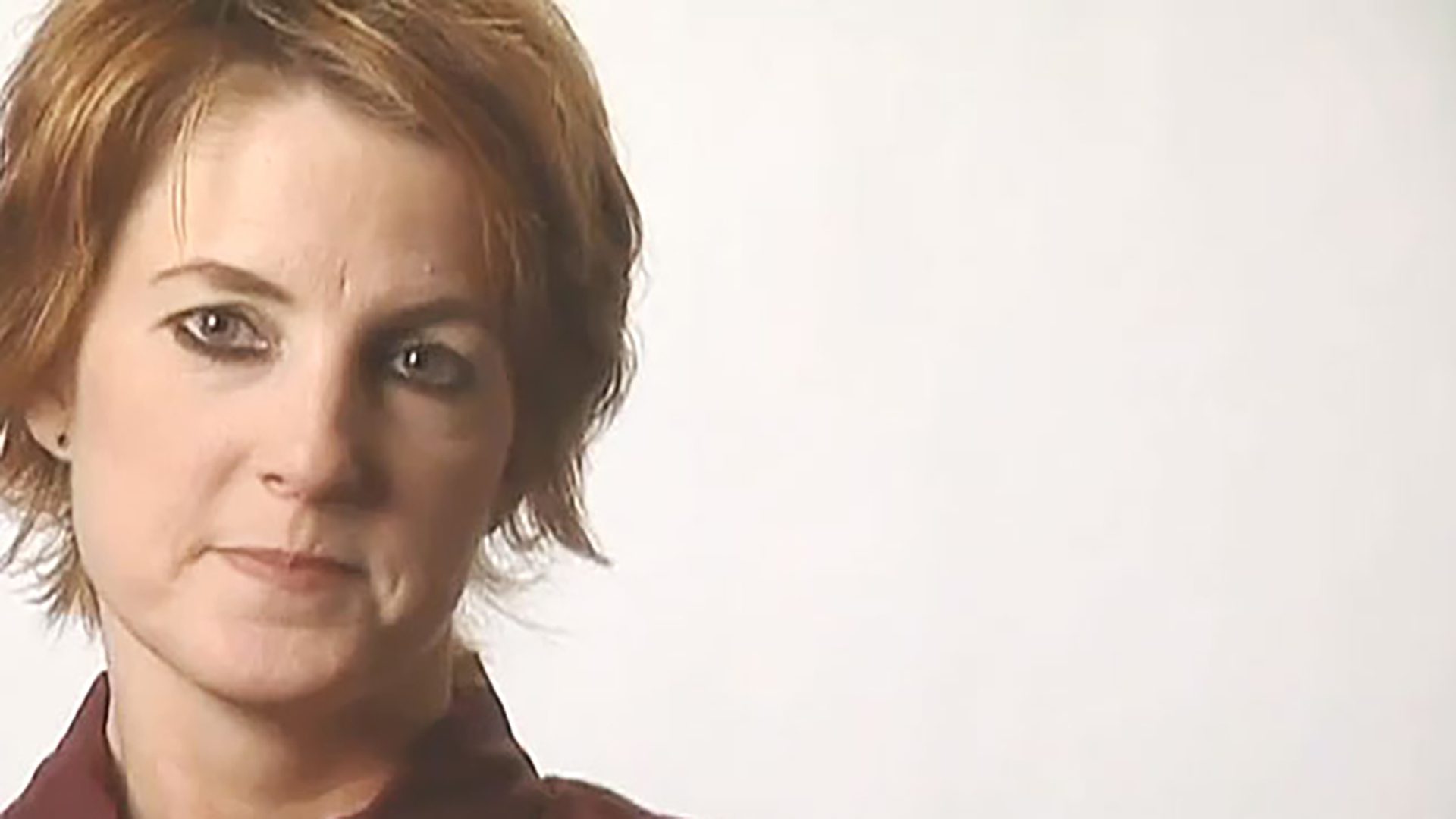 A Portrait Of A Woman With Short Hair Wearing Eye Makeup And A Maroon 