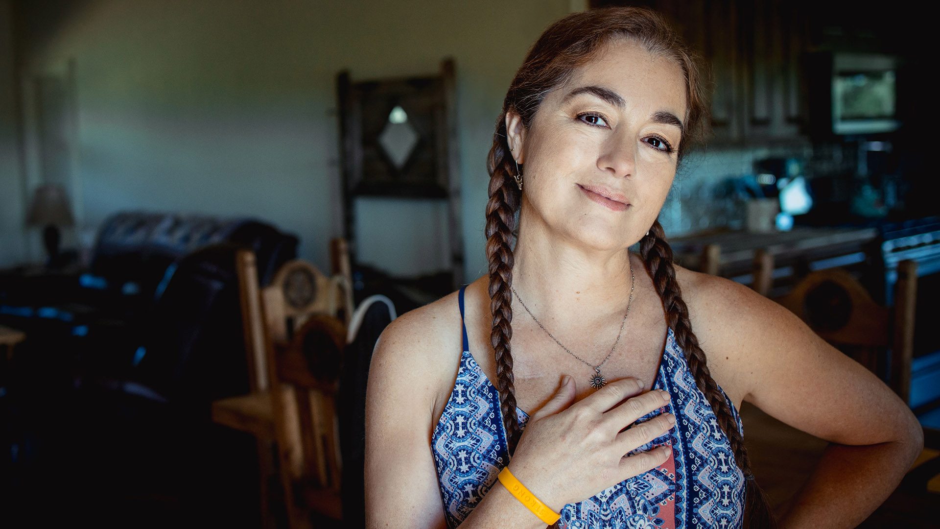 A middle aged woman with braids poses with Livestrong wristband