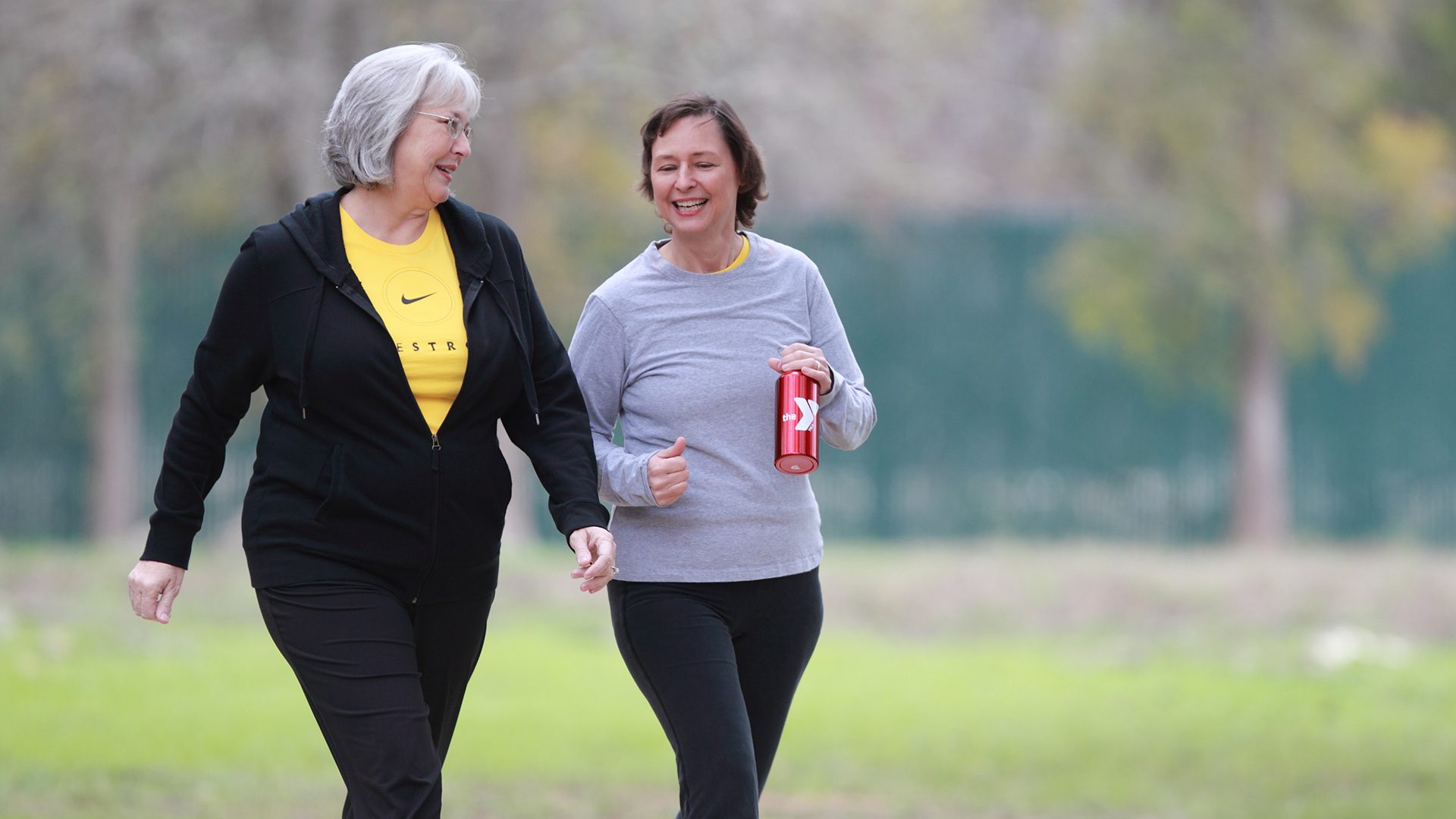 A senior woman and a middle aged woman walking in a park