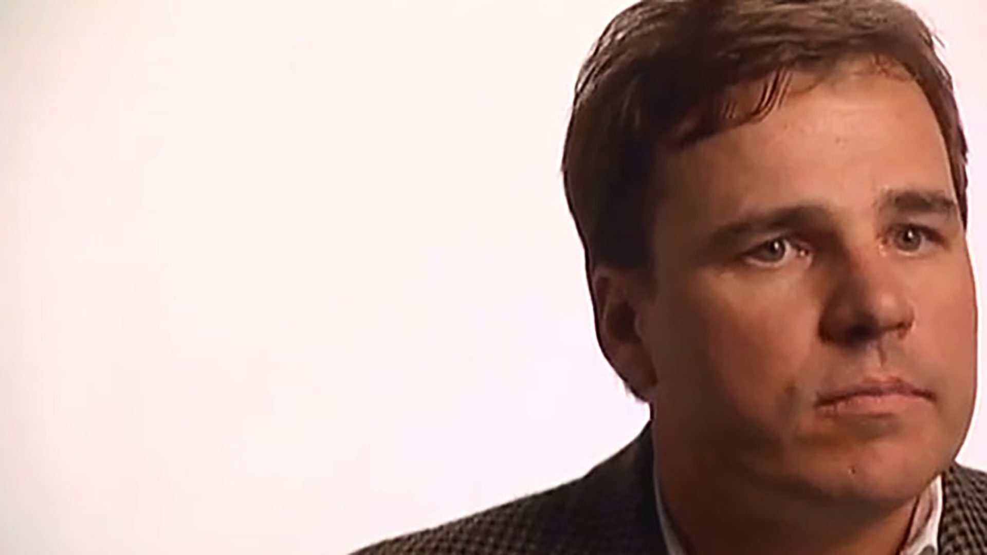 A close-up image of an adult man being interviewed against a white background