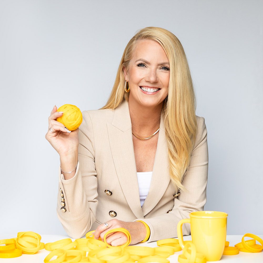 A woman sitting at a table surrounded by yellow Livestrong wristbands