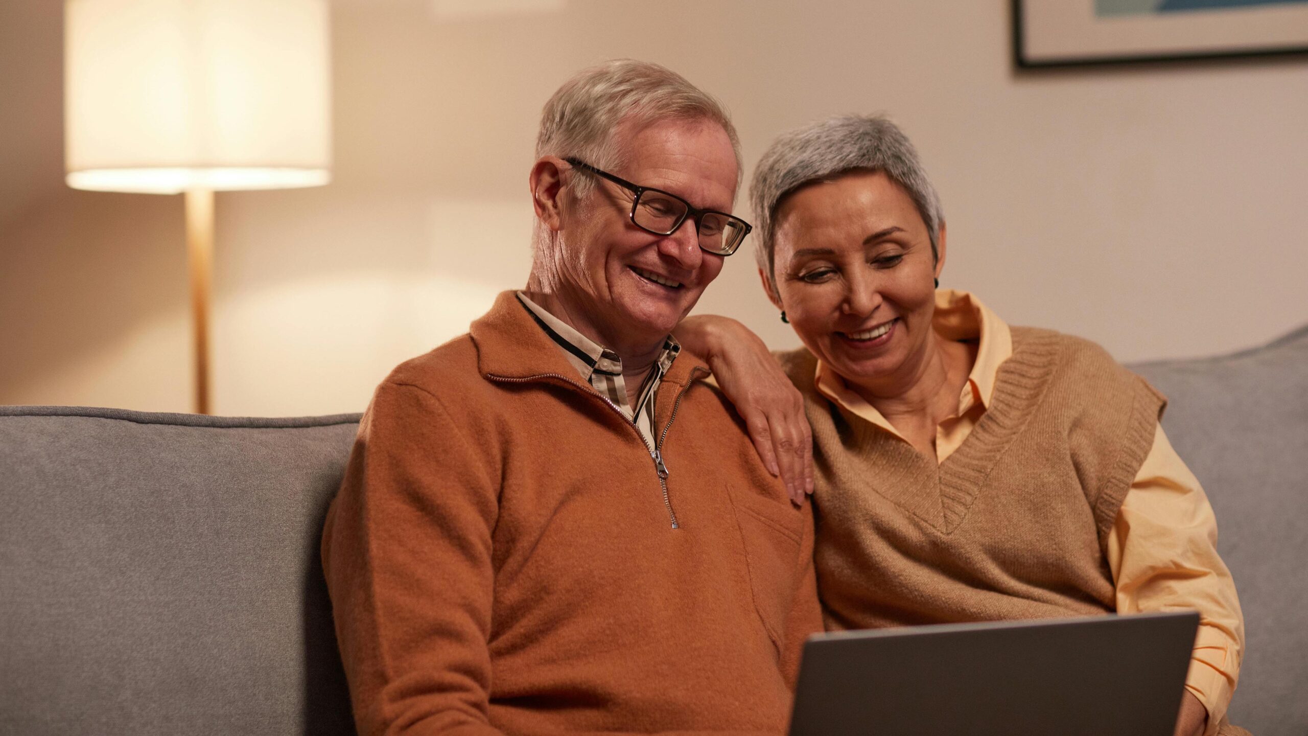 Senior couple sitting on couch and looking at laptop