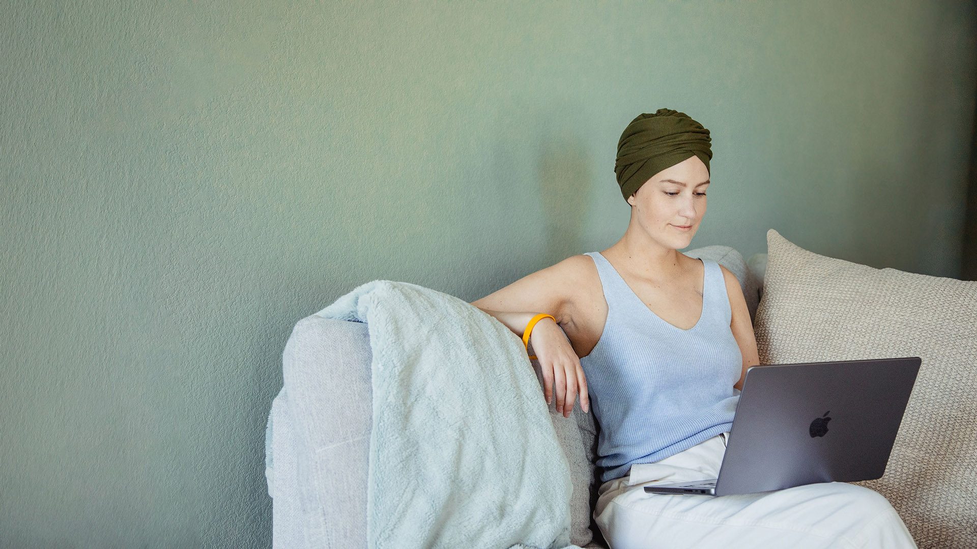 A female cancer patient sitting on the couch using a laptop