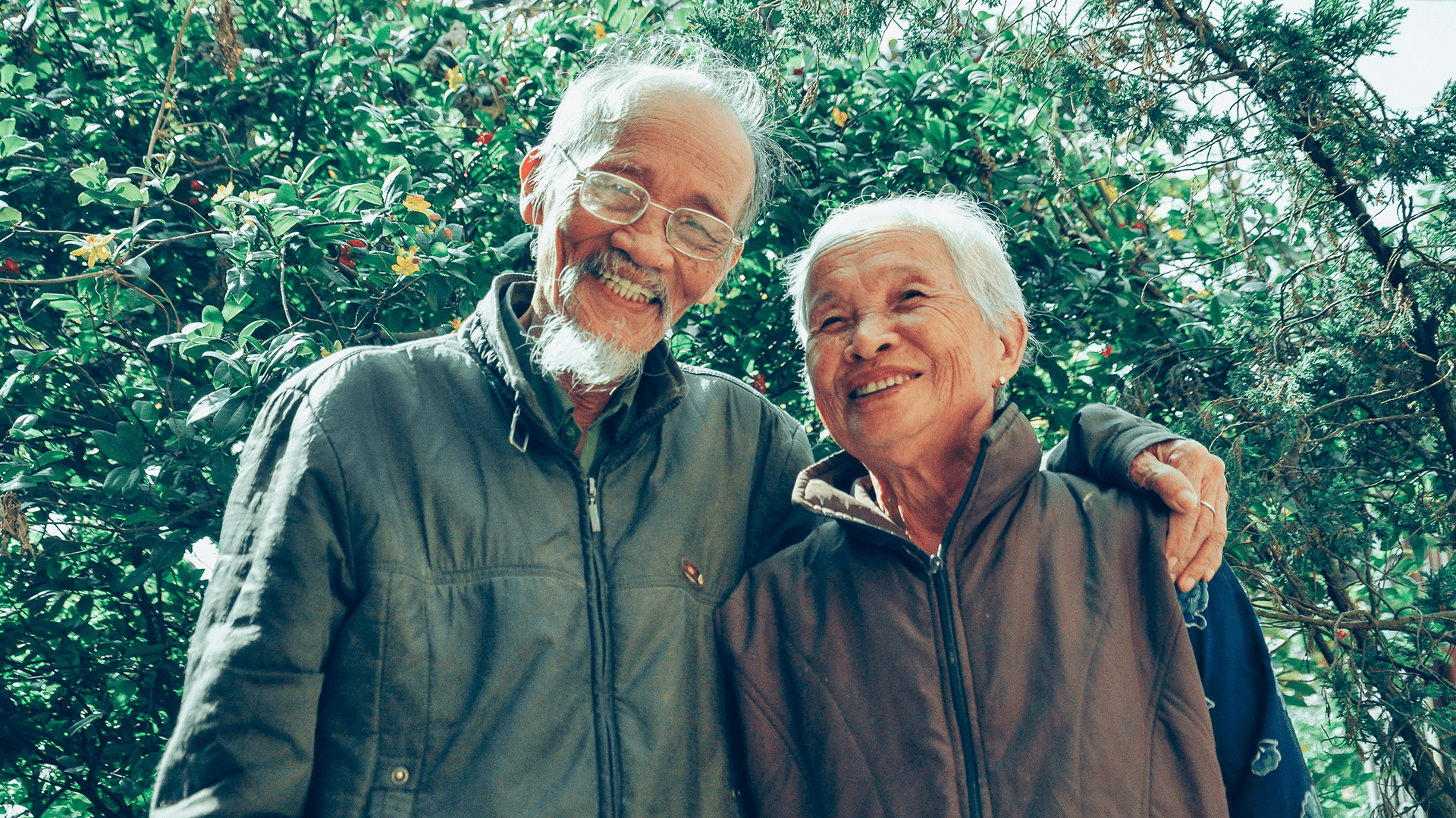 A senior man and woman smiling in a garden