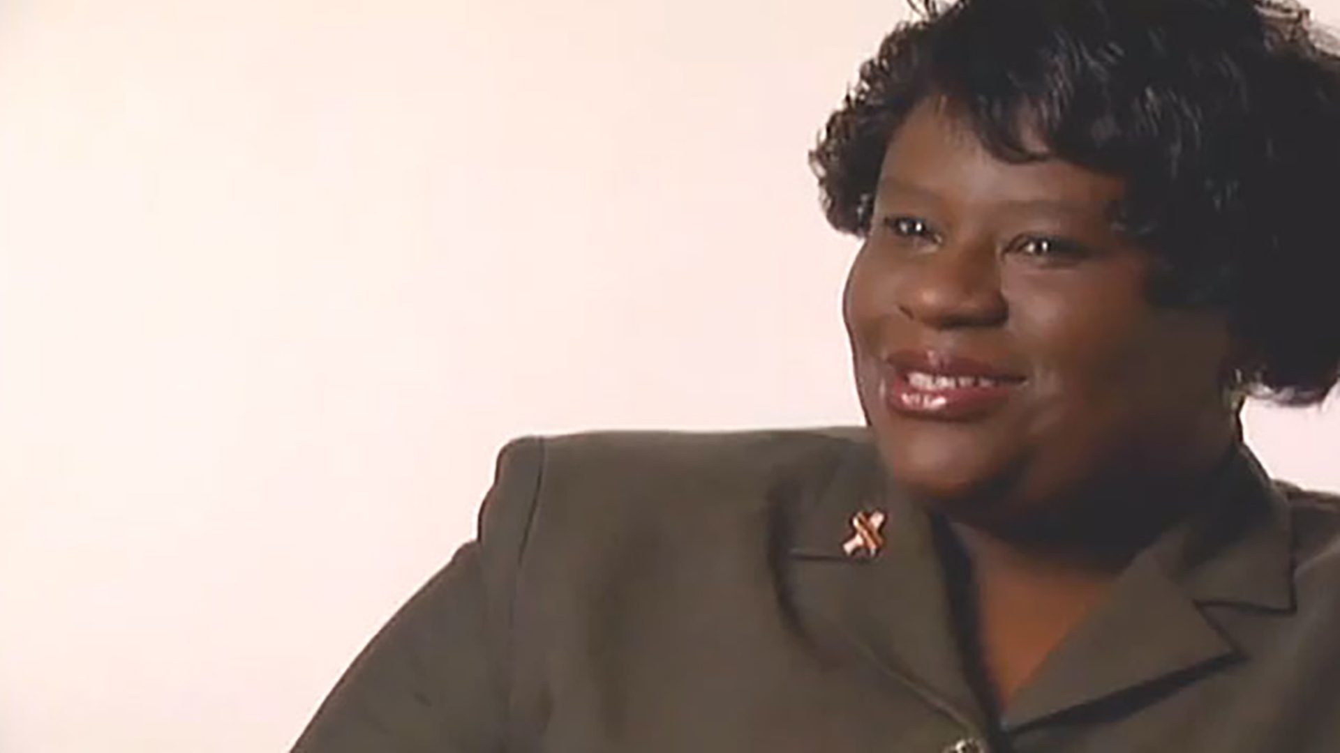 A woman wearing a suit jacket being interviewed against a white background.