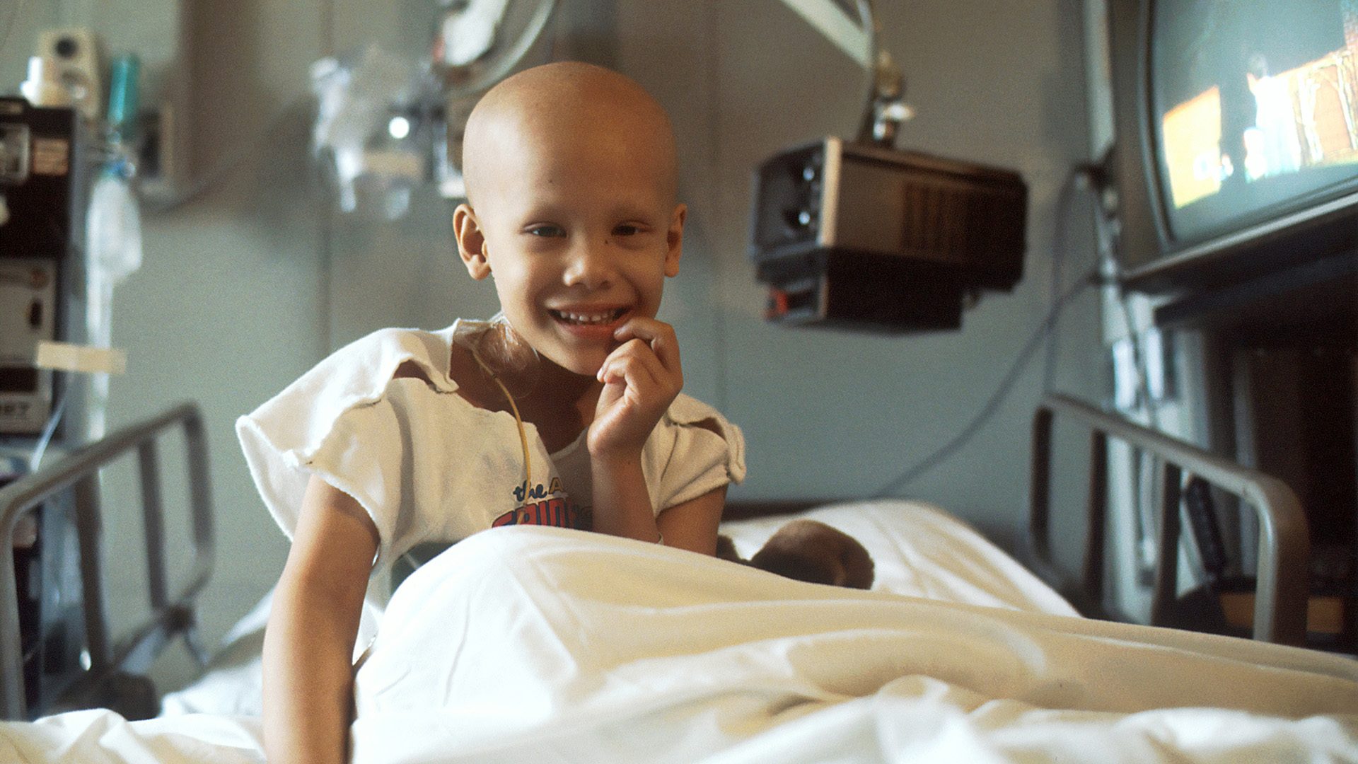 A young girl in a hospital bed receiving cancer treatment