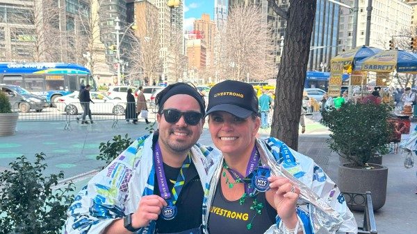 NYC Half Marathon runners smiling and holding up their finisher medals.