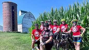 Livestrong cyclists posing in front of a barn, silo and corn stalks in Iowa at RAGBRAI.