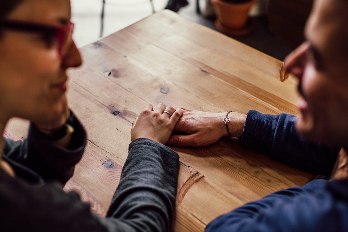 Two people hold hands while sitting at a table