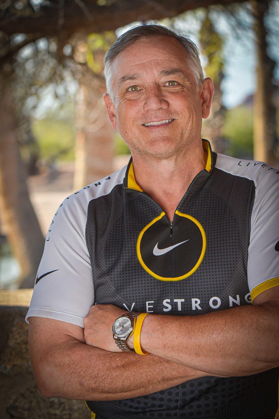 A smiling middle aged man outdoors wearing Livestrong gear
