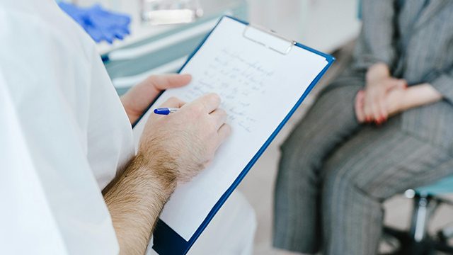 A medical professional writing patient information on a clipboard