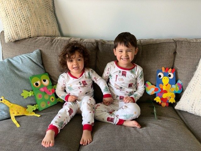 Two young children sit on the couch wearing matching pajamas