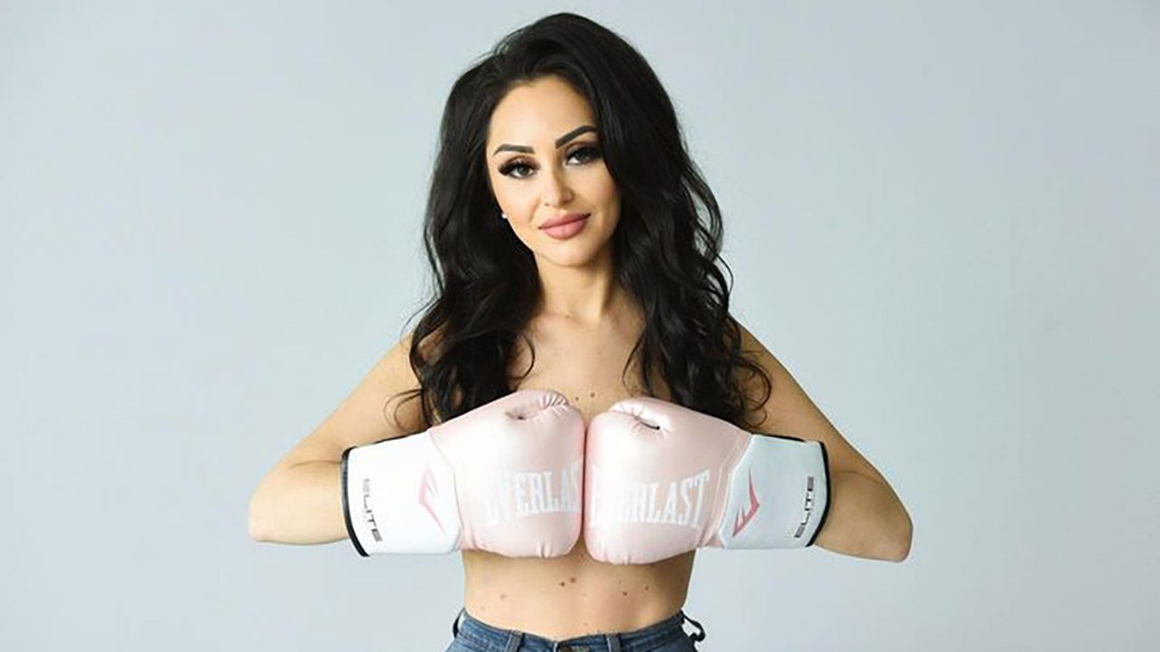 A young woman holding pink boxing gloves over her chest