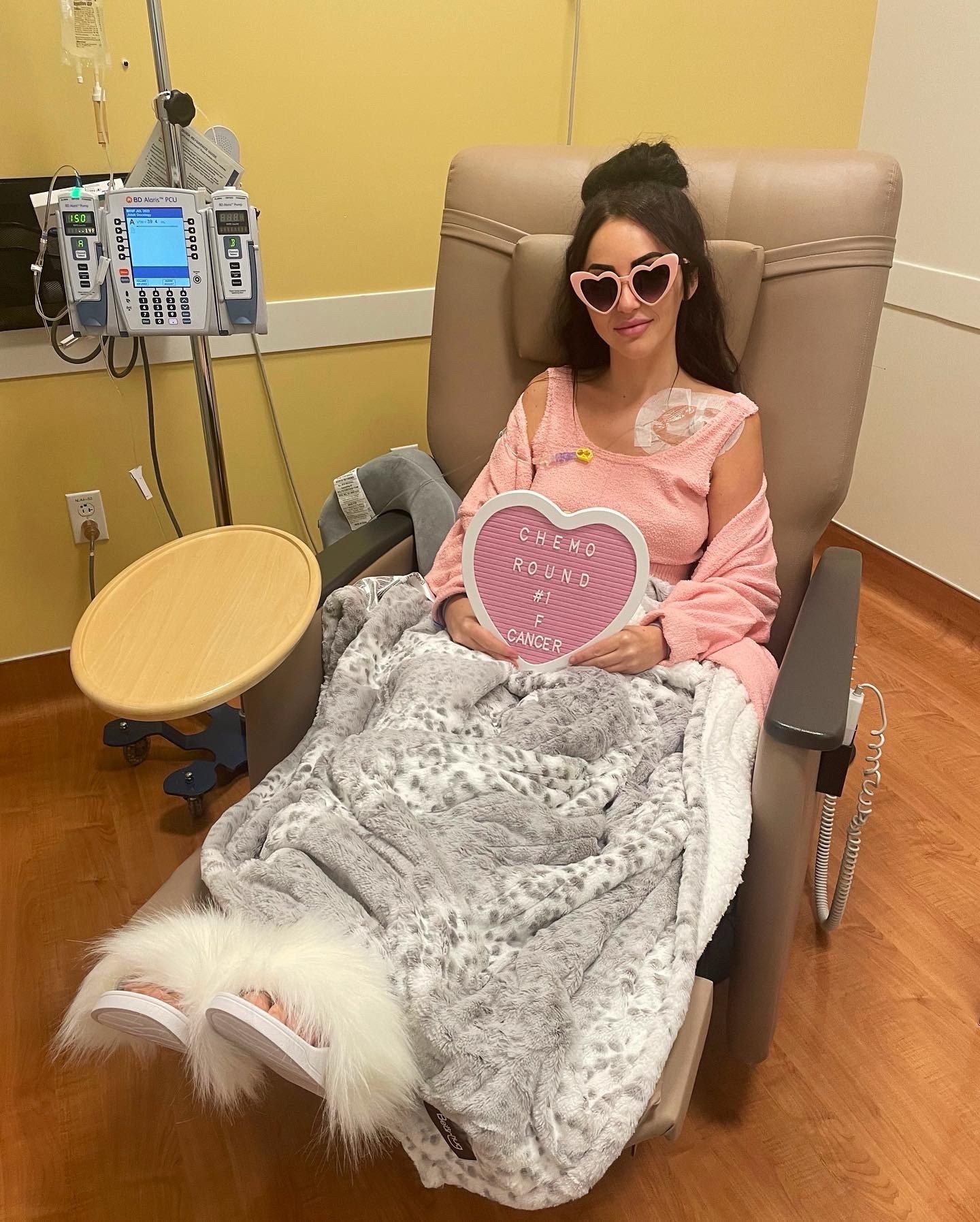 A young woman wearing pink clothing sitting in a hospital chair