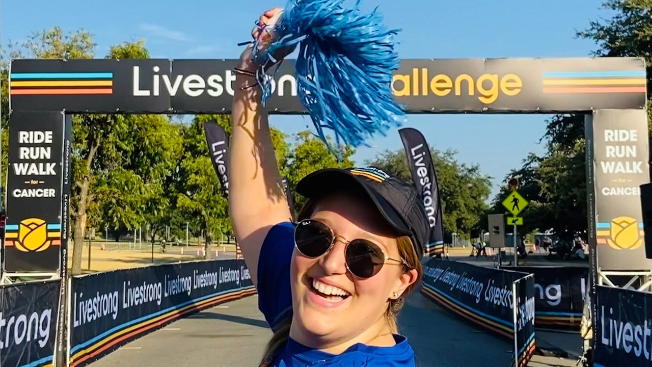 A young woman waving a pom pom at a run finish line