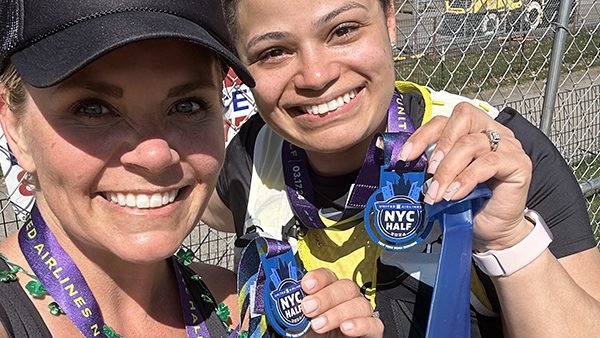 Two women holding up NYC Half marathon medals