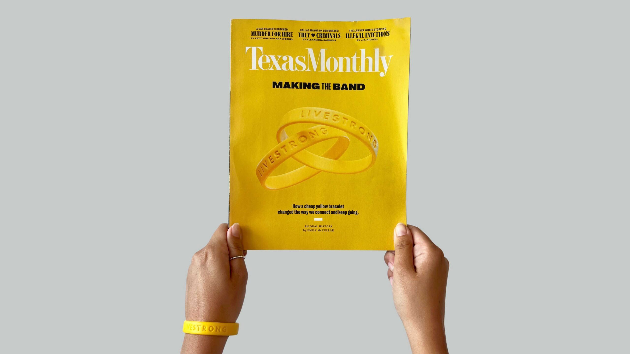 Two hands, one wearing a yellow wristband, hold a yellow magazine