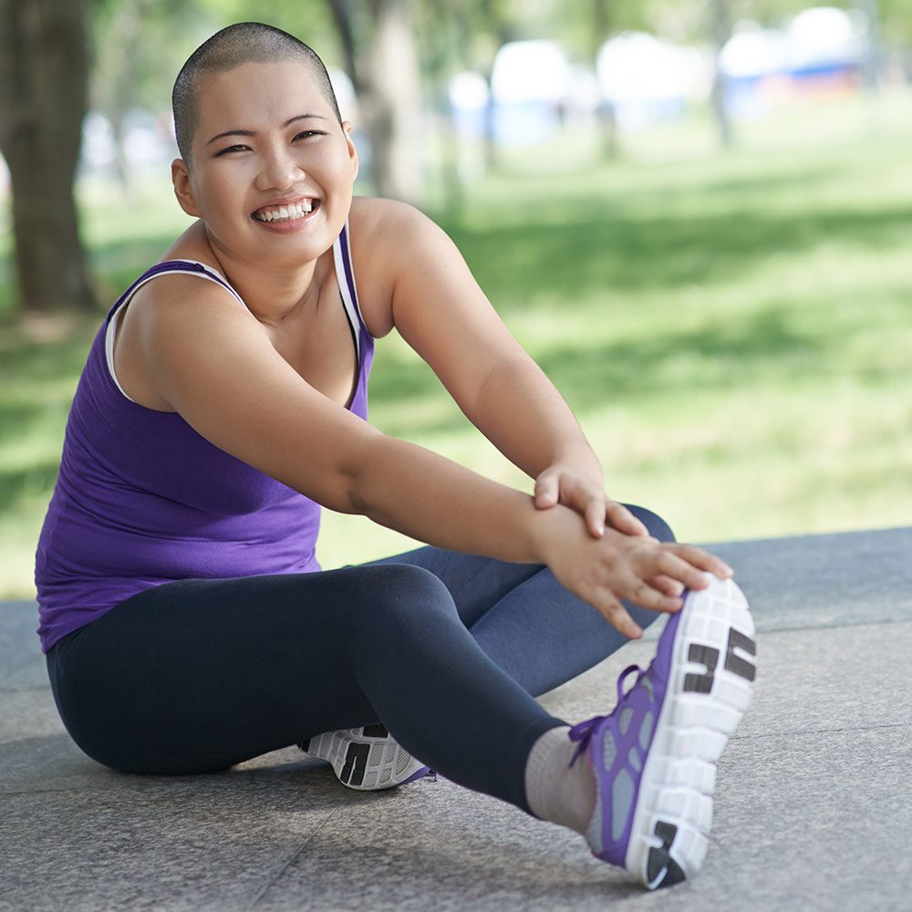 A young woman smiling and stretching outdoors