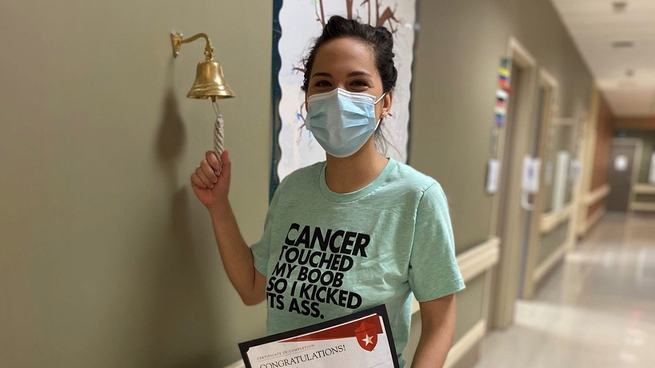 A woman ringing a bell holding a certificate of congratulations