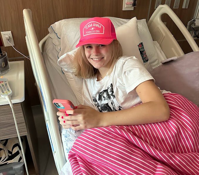 A girl in a hospital bed wearing a pink hat and blanket