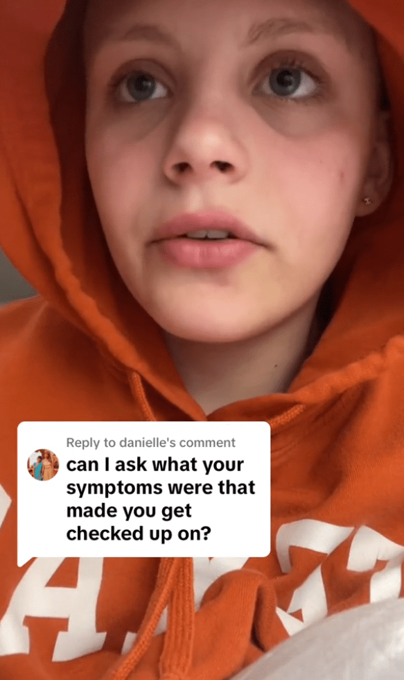 A teen girl wearing an orange hoodie speaks on camera for TikTok