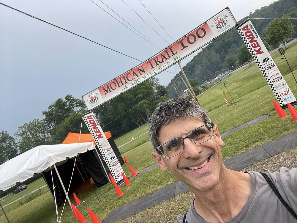 A man smiling in front of a race start line