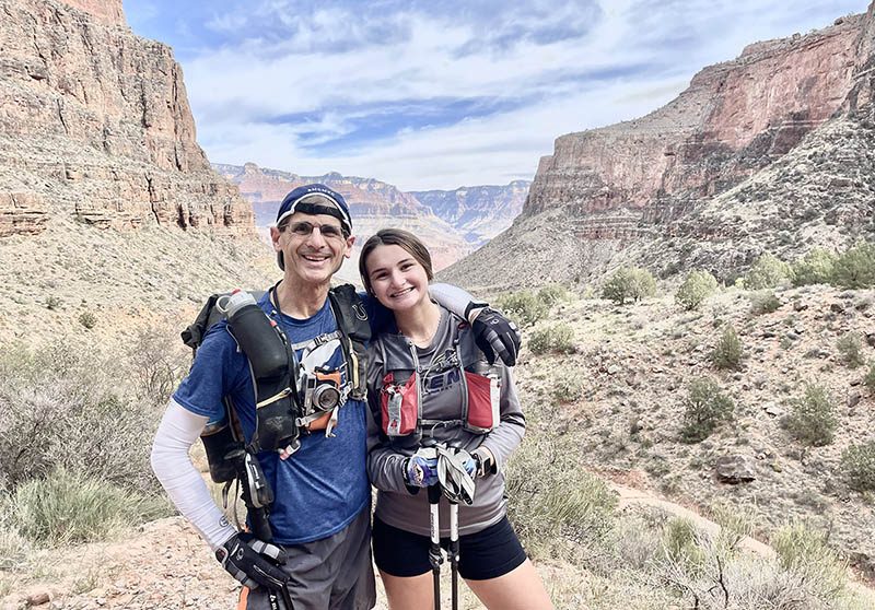 A father and daughter hike in a canyon