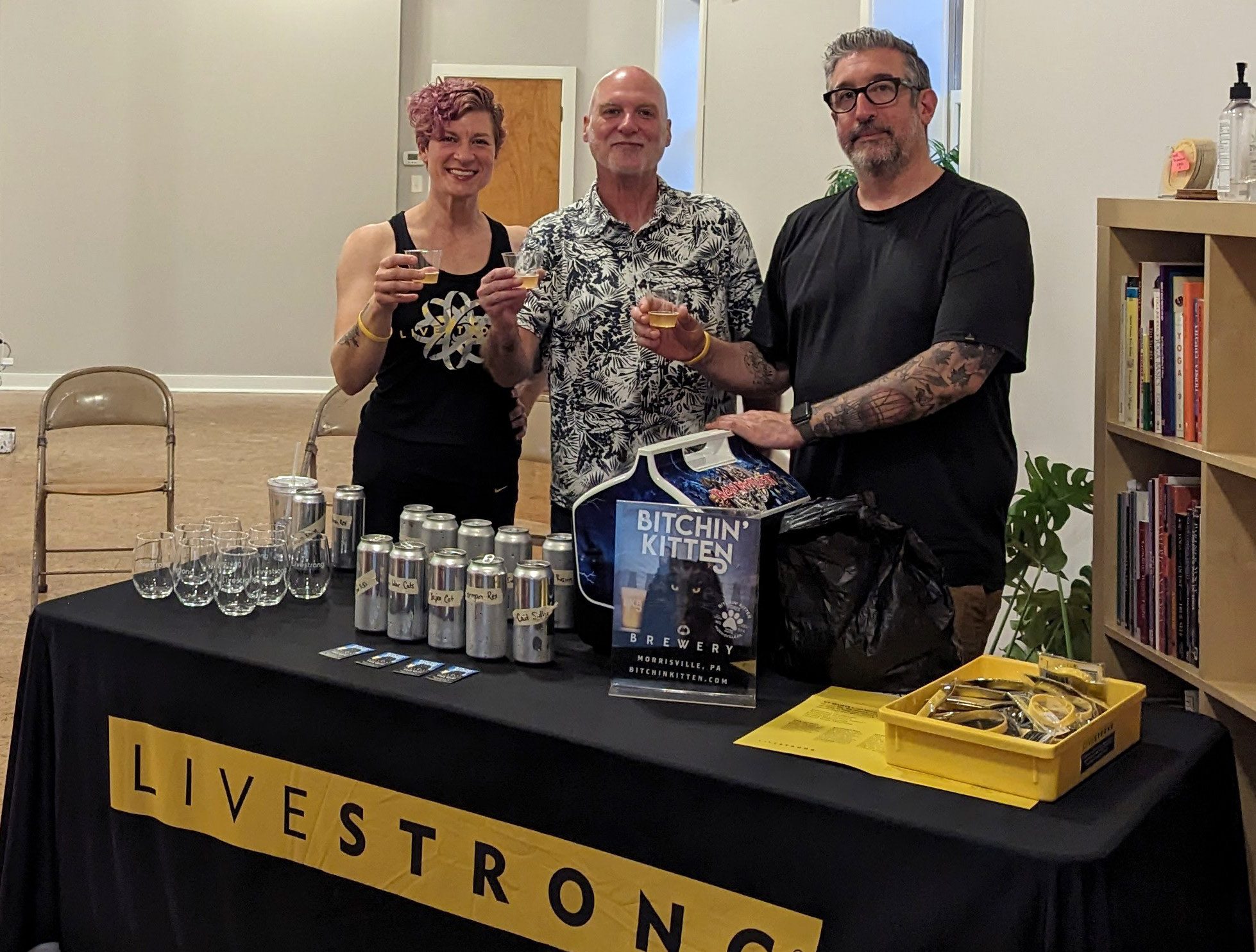 3 people hold cups of beer at a table