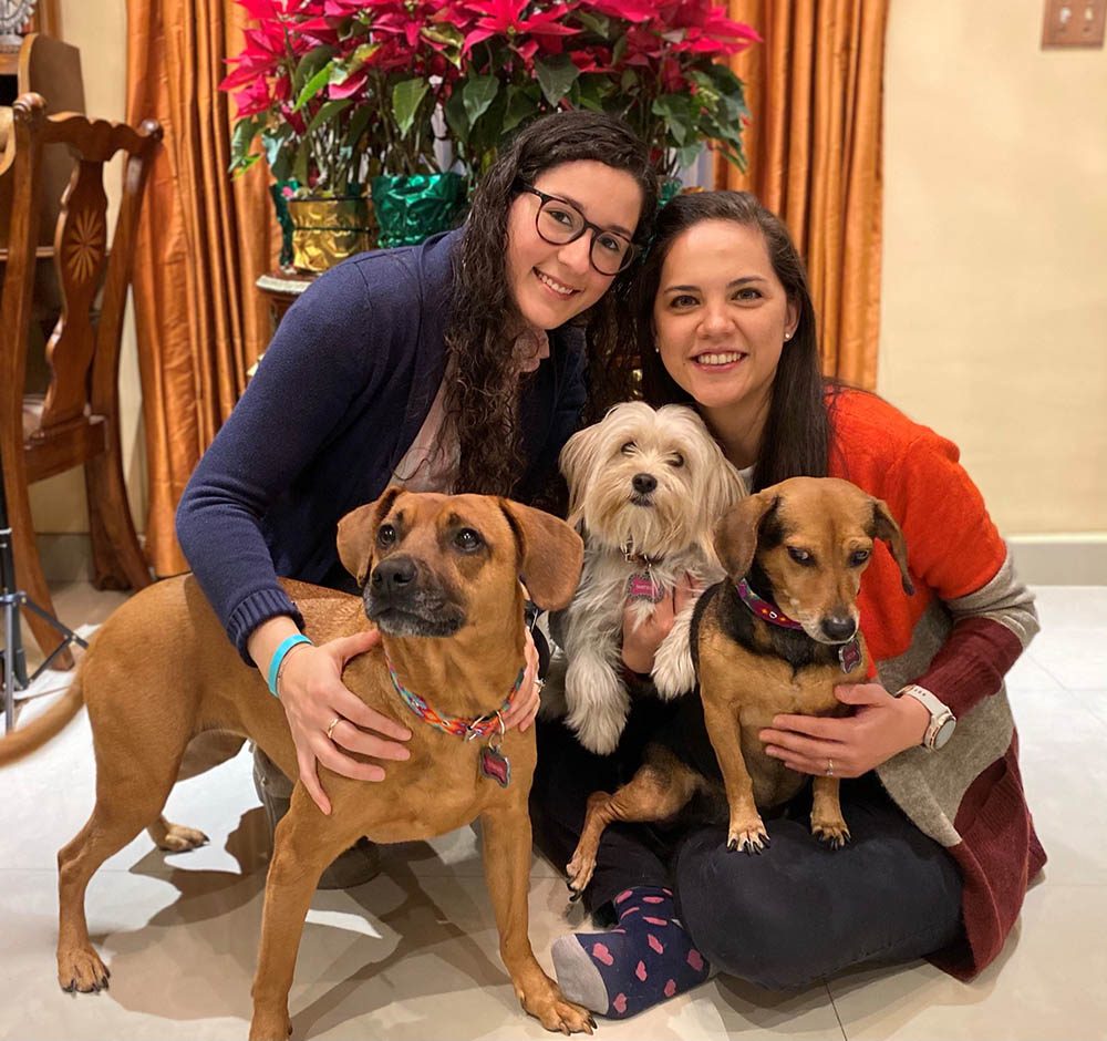 Two women pose with three dogs