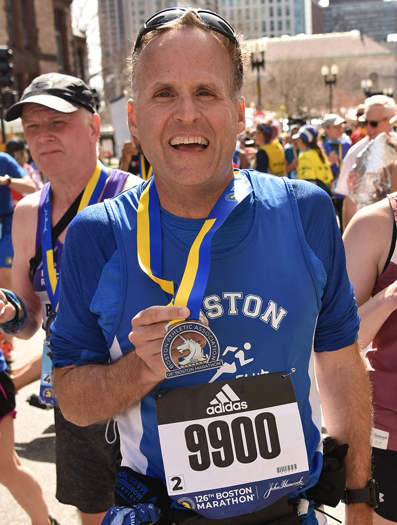 Man smiling with a medal after finishing a marathon