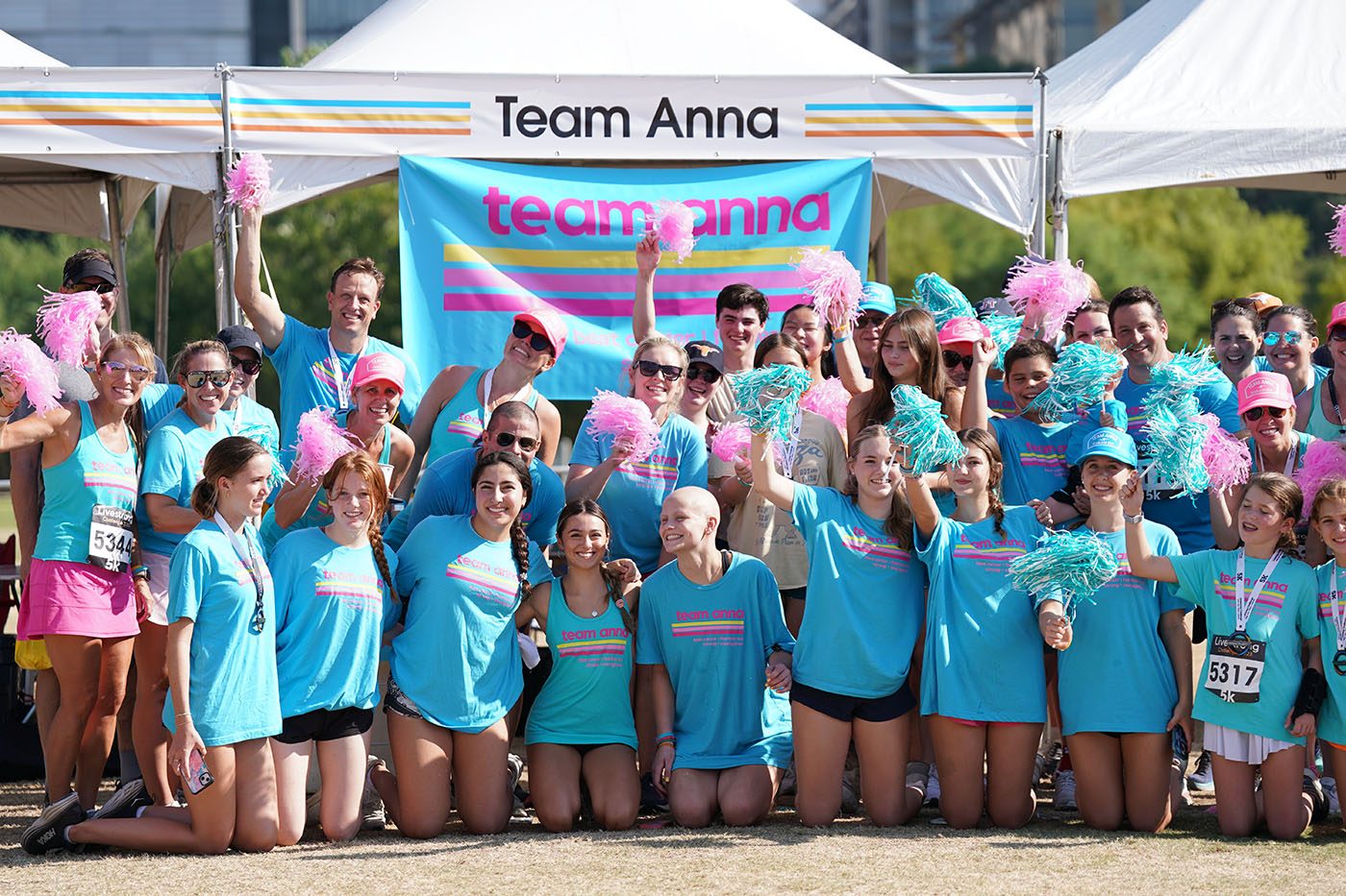 A team wearing matching blue T-shirts and waving pom poms