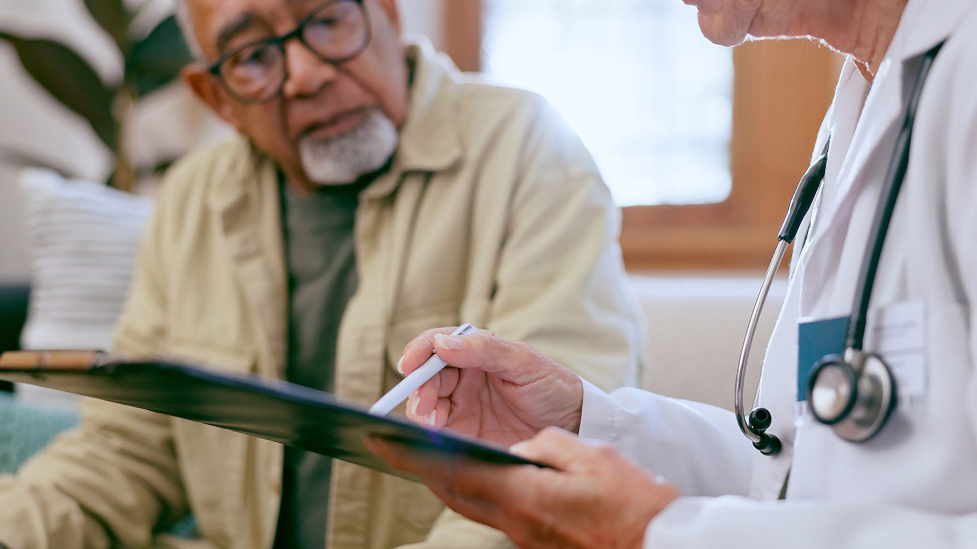 A doctor pointing to a clipboard, showing results to a senior man