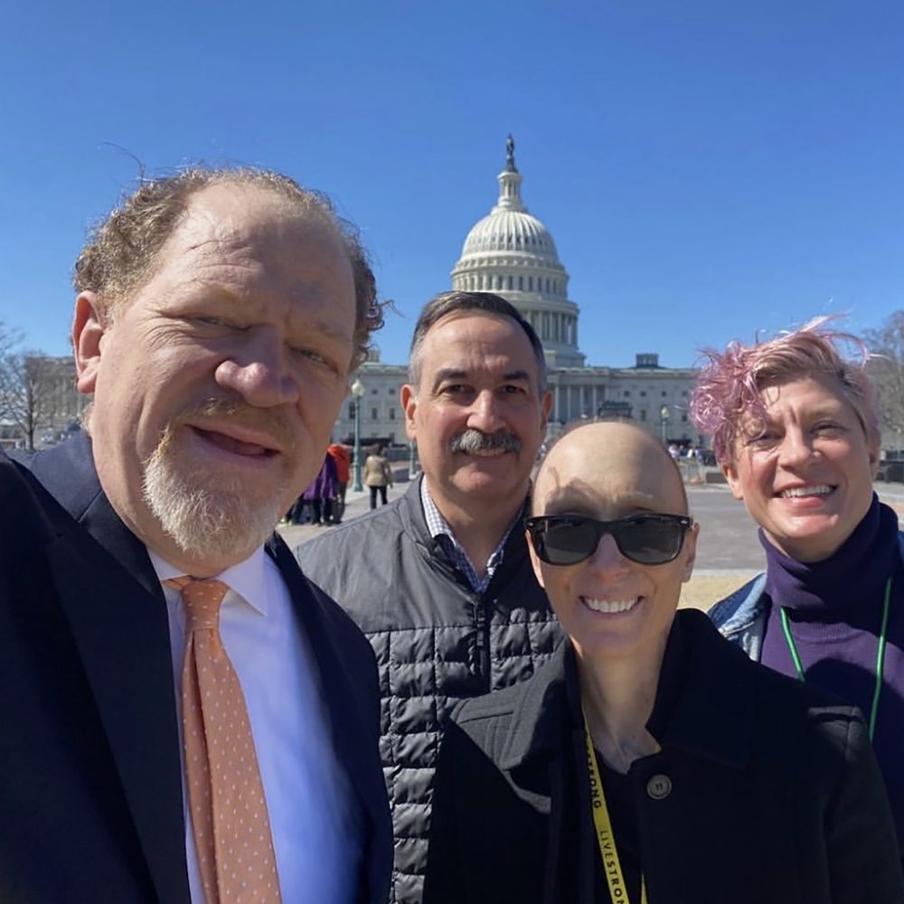 4 adults smiling in front of the United States capitol