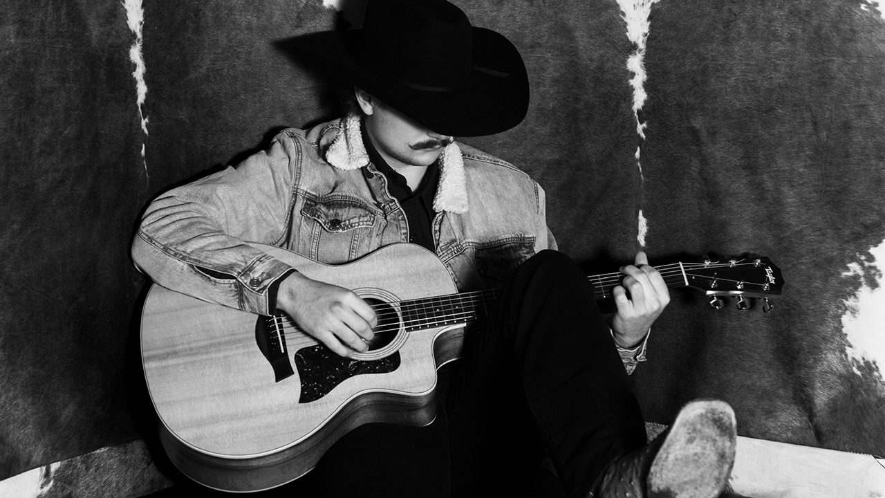 A man in a cowboy hat playing guitar