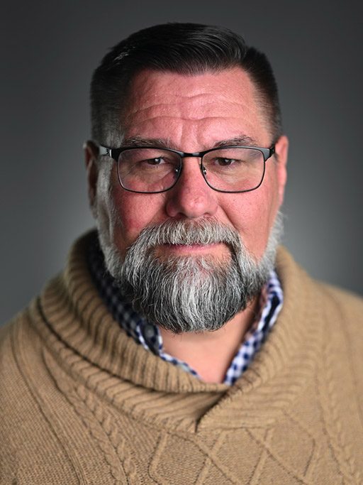 Headshot of an adult man with a beard and glasses
