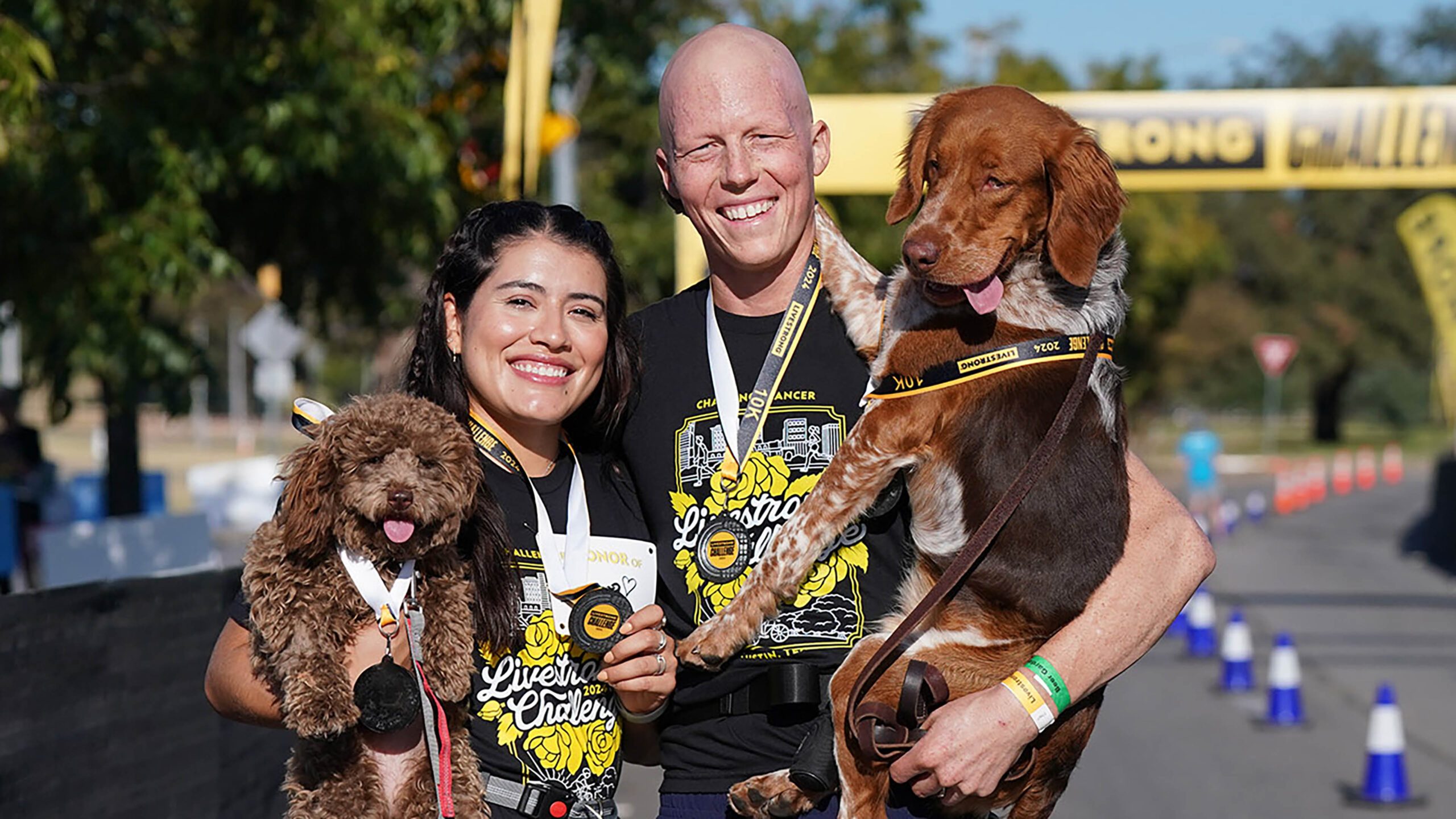 2 young adults and 2 dogs at the finish line of a run