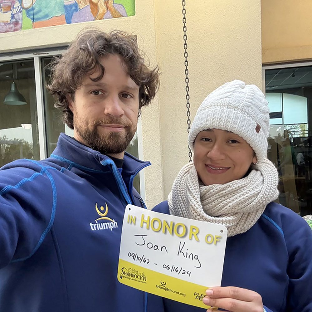 A man and woman taking a selfie with an "in honor of" sign