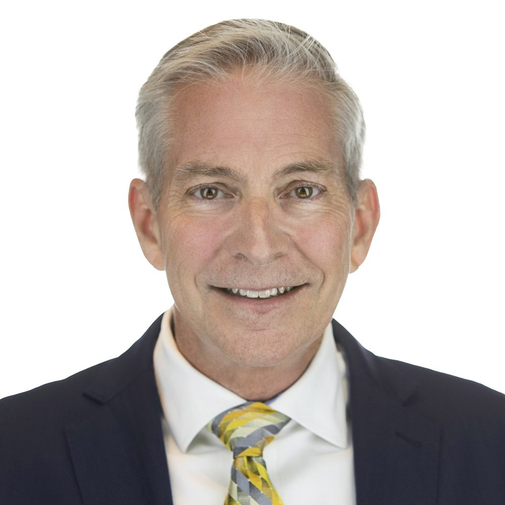 A professional portrait of an adult man wearing a suit