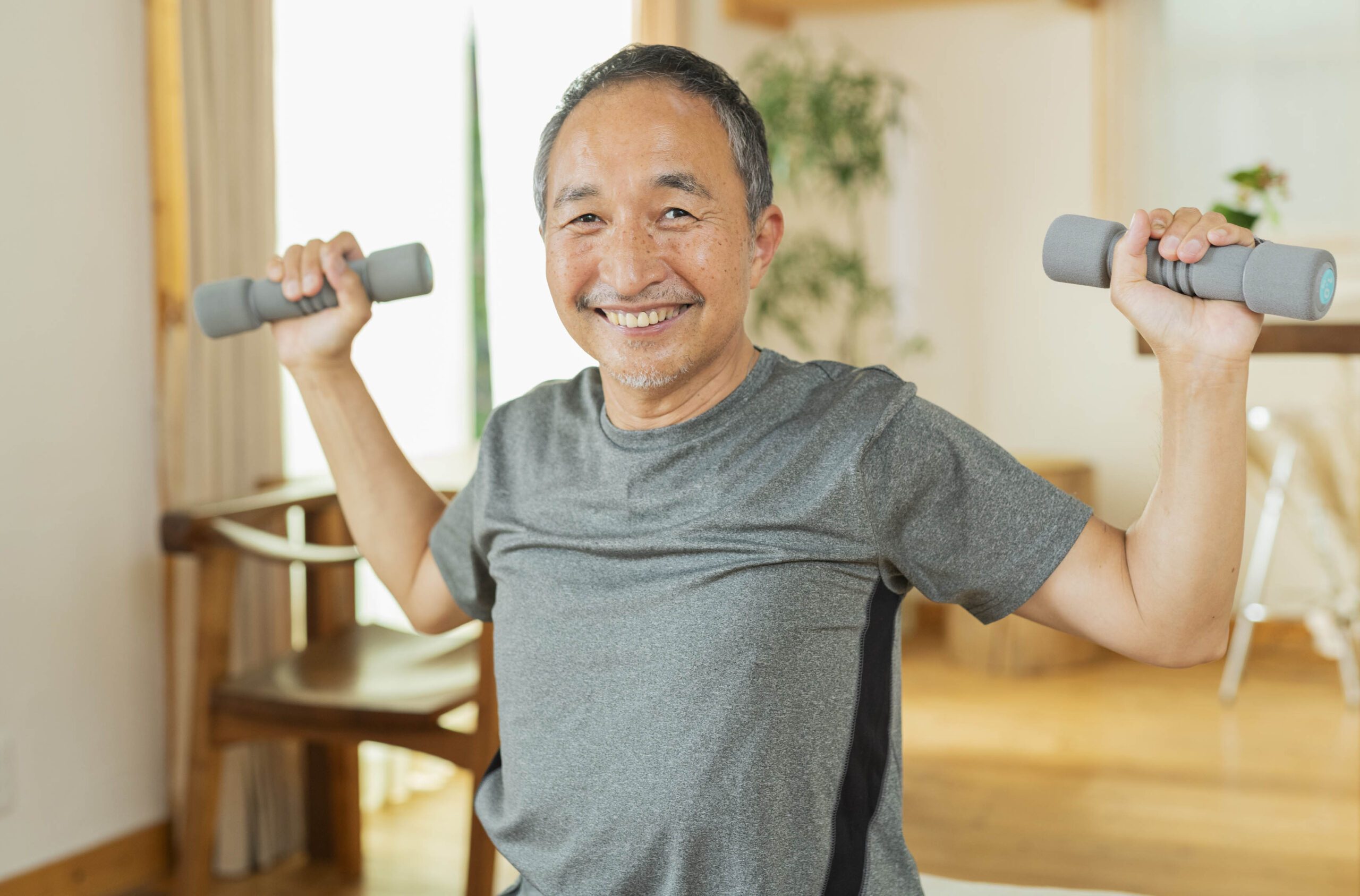 Adult man at home lifting dumbbells and smiling