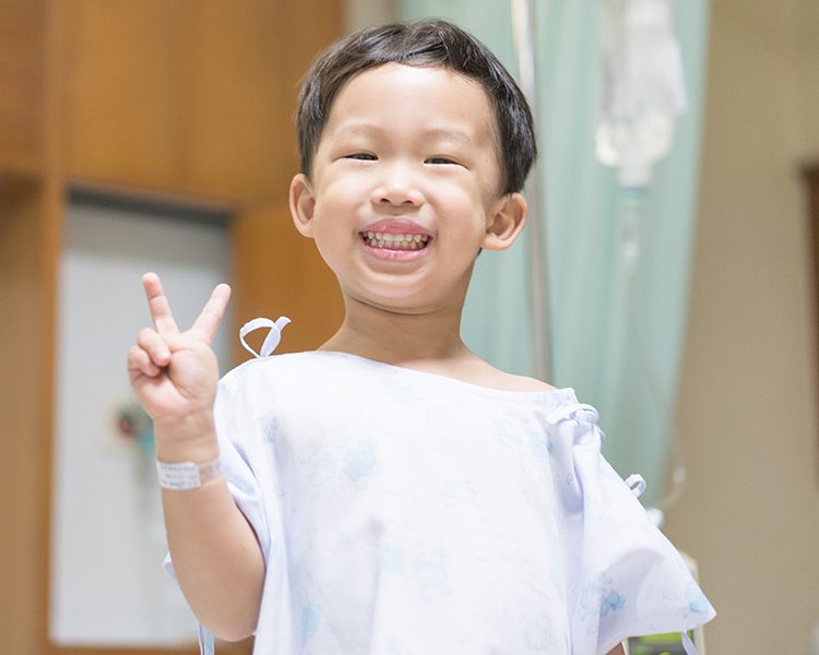 Happy young boy in the hospital posing with a peace sign