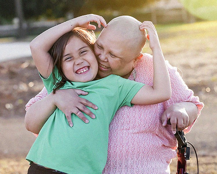 Mother with hair loss hugging child in park
