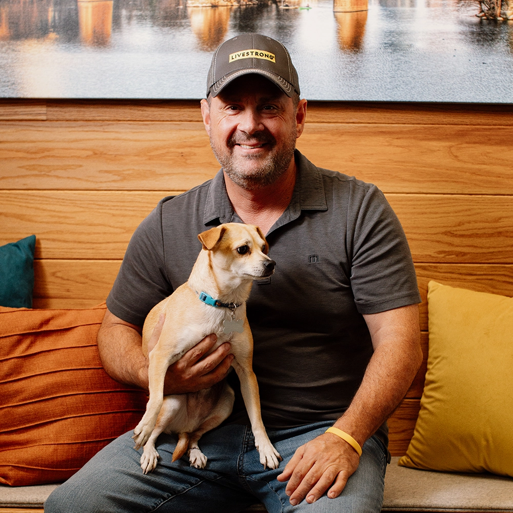 A man wearing Livestrong merchandise holding a small dog